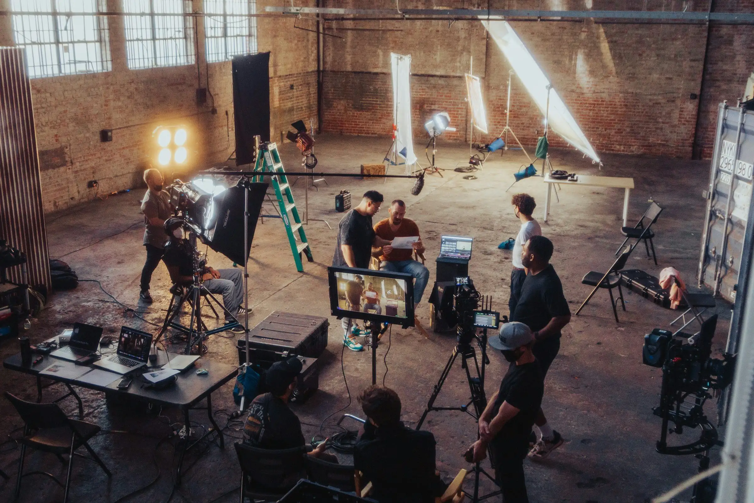 A film crew lighting a set inside a brick warehouse studio